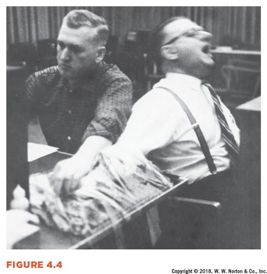 Black-and-white photograph of a distressed male participant leaning back with his mouth open during the Milgram study.