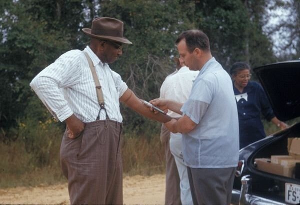 A U.S. Public Health Service worker draws blood from the arm of a Black man participating in the Tuskegee study.