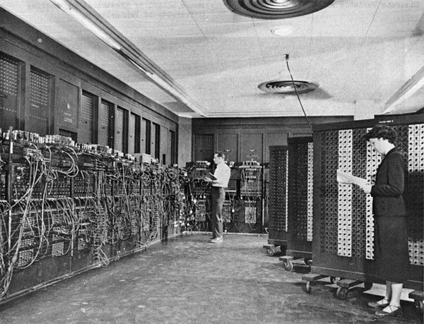 The ENIAC, a room-sized 1940s computer with two operators adjusting cables.
