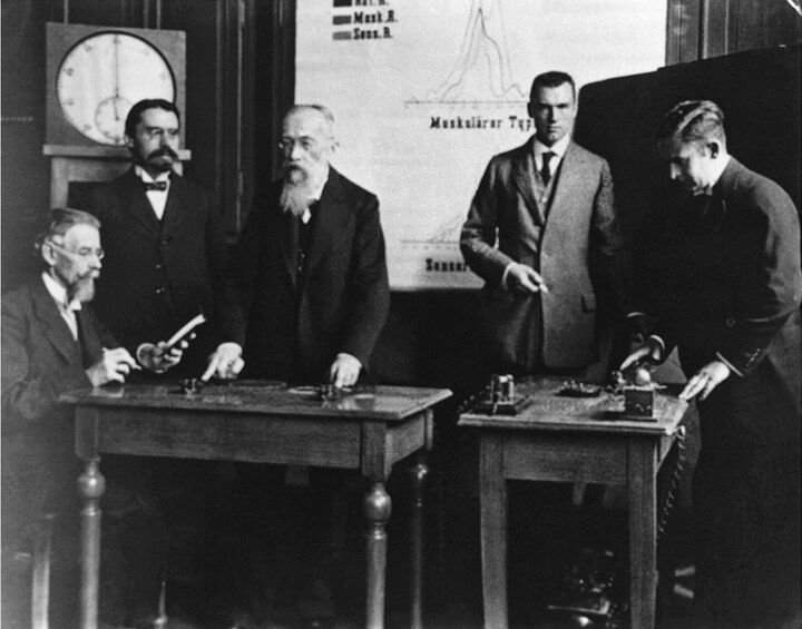 Historic photograph of Wundt's Leipzig laboratory: men in suits gathered around tables of brass reaction-time apparatus.