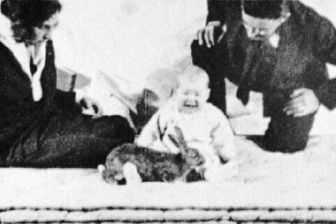 Black-and-white photo of Little Albert crying, with a furry animal in front of him and the researchers nearby.