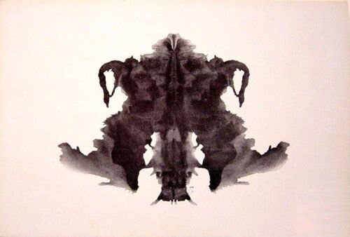 A symmetrical black Rorschach inkblot resembling a bat or winged figure.