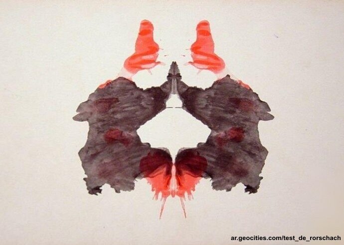 A symmetrical Rorschach inkblot in black with red patches at the top and bottom.