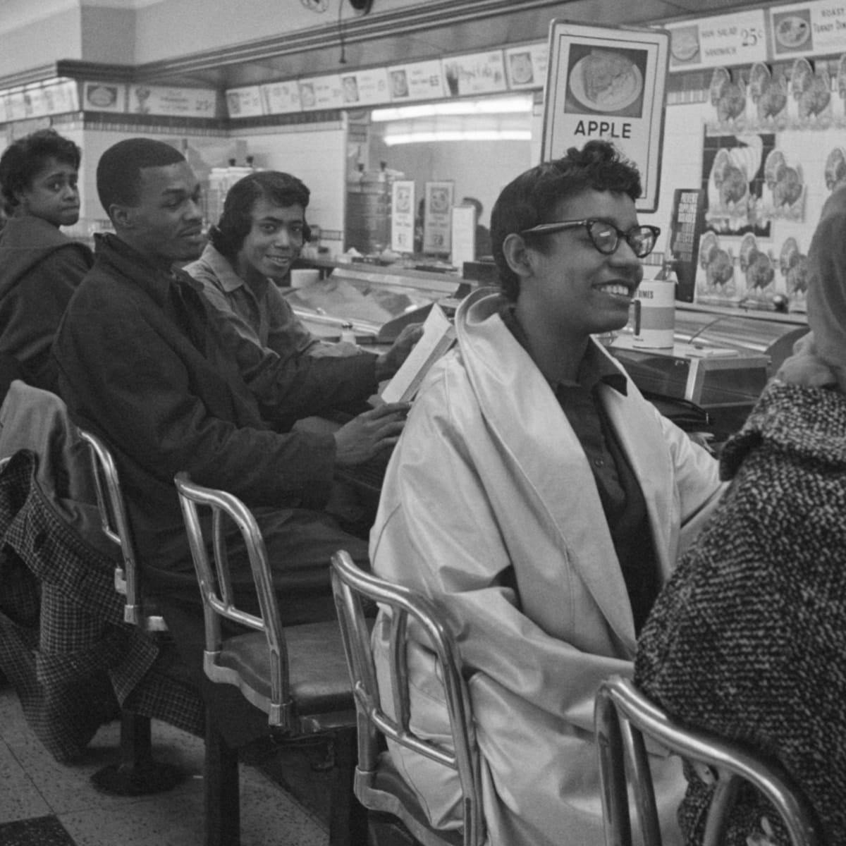 Teenagers seated at a mid-century lunch counter being served.