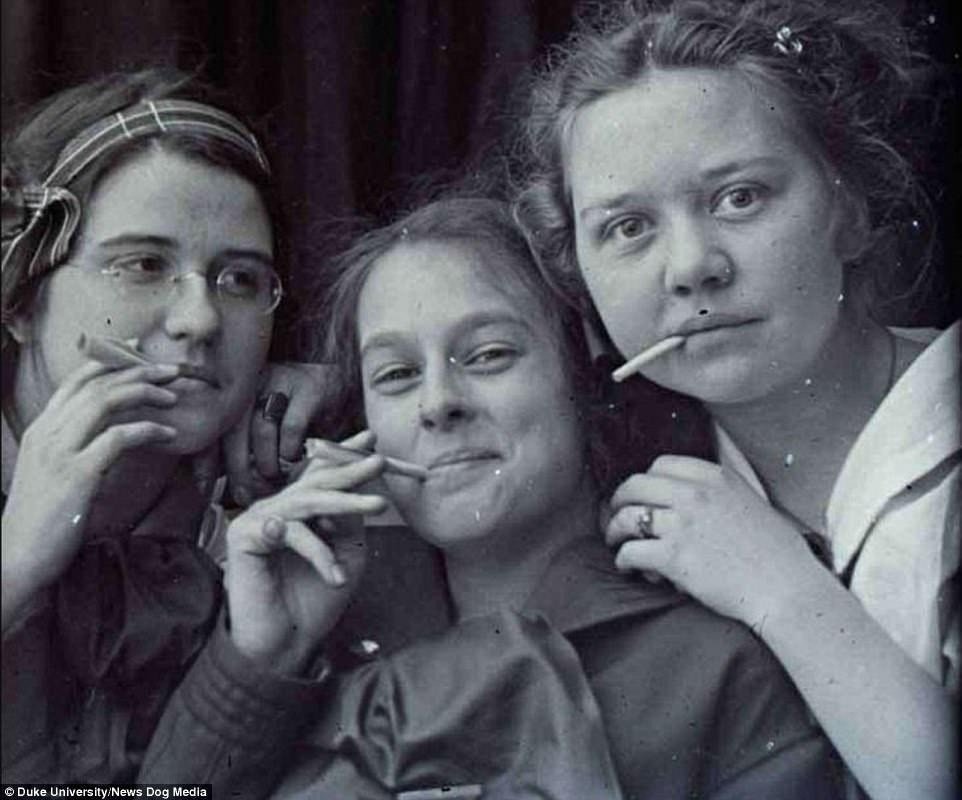 Three young women smoking cigarettes in a vintage photograph.