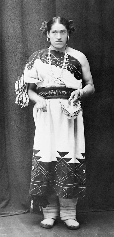 Nineteenth-century studio photograph of a Native American Two-Spirit person in traditional dress.
